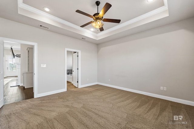 unfurnished bedroom with a tray ceiling, ceiling fan, and carpet