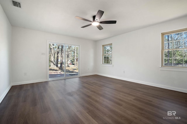 spare room with ceiling fan, dark wood finished floors, visible vents, and baseboards