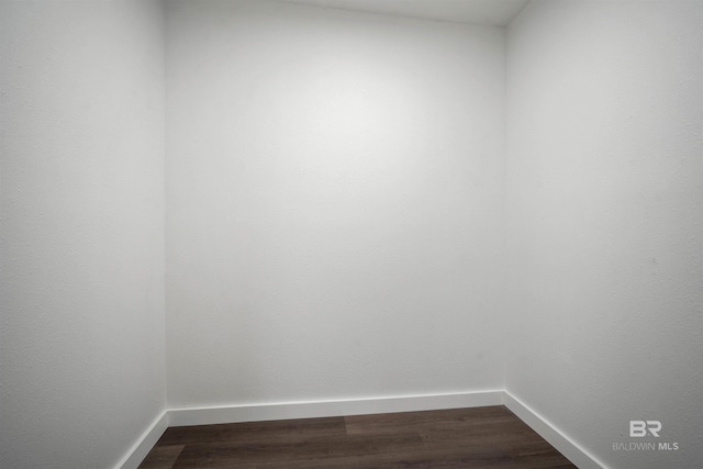 empty room with dark wood-style flooring and baseboards