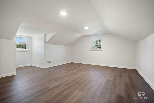 bonus room with lofted ceiling, baseboards, dark wood-style flooring, and a wealth of natural light