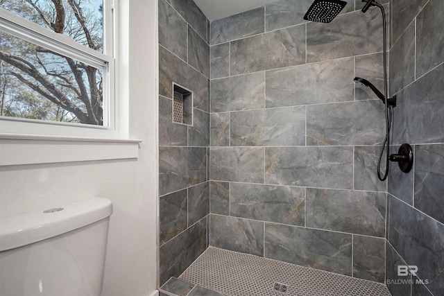 bathroom with a tile shower and toilet