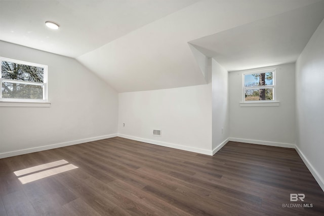 additional living space featuring lofted ceiling, visible vents, dark wood finished floors, and baseboards