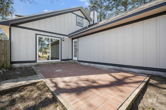 rear view of property featuring board and batten siding, a patio area, and fence