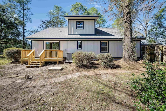 back of house with central AC, roof with shingles, and a wooden deck