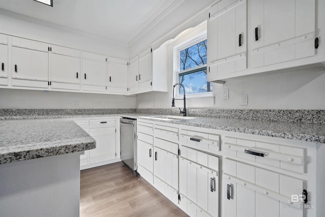 kitchen featuring light wood-style floors, white cabinetry, ornamental molding, and a sink