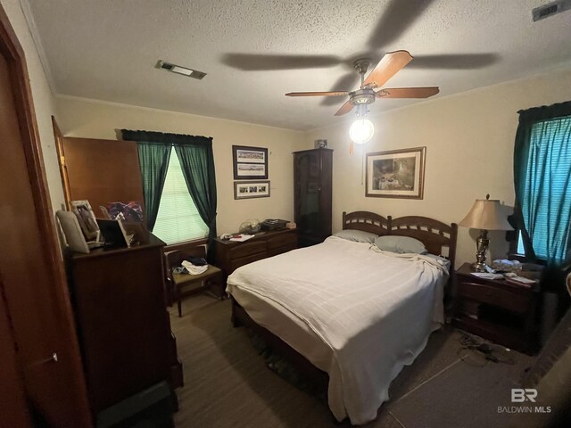 carpeted bedroom with visible vents, a ceiling fan, and a textured ceiling