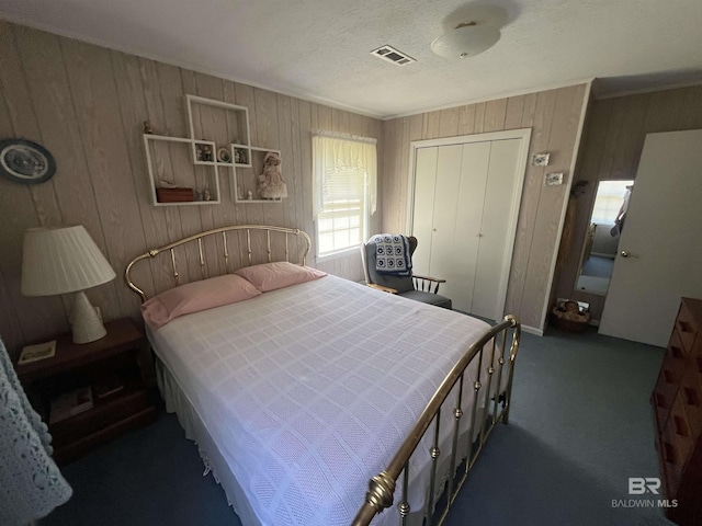 carpeted bedroom featuring visible vents, ornamental molding, wooden walls, and a closet