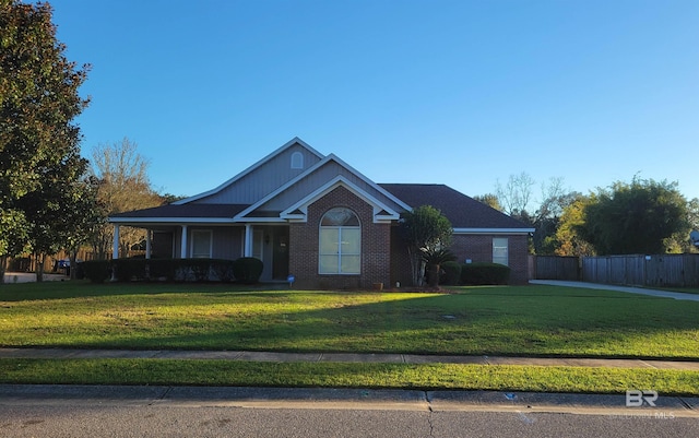 view of front of property featuring brick siding, covered porch, a front yard, and fence