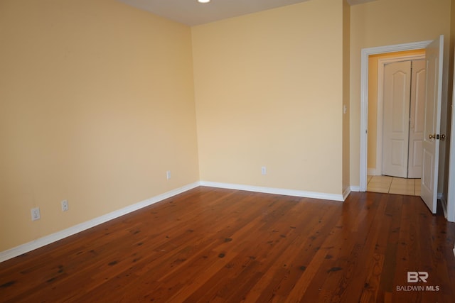 unfurnished room featuring baseboards and dark wood finished floors