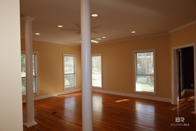 empty room featuring crown molding, baseboards, decorative columns, wood finished floors, and a ceiling fan