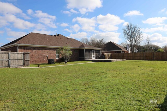 view of yard featuring central air condition unit, a fenced backyard, and a sunroom