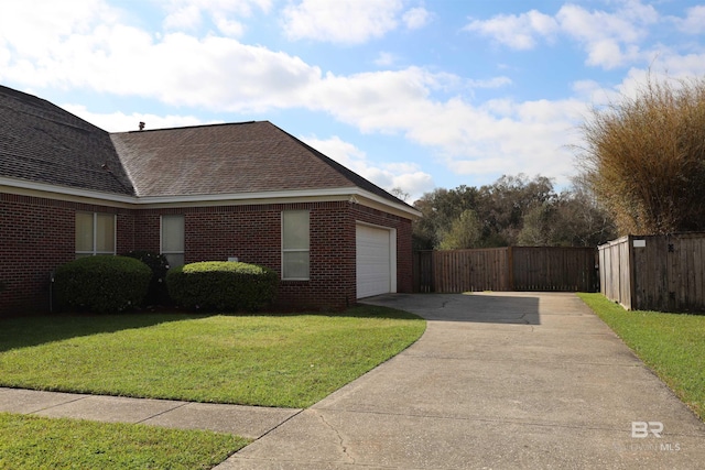 view of home's exterior with driveway, fence, a yard, an attached garage, and brick siding