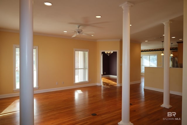 unfurnished living room featuring decorative columns, wood finished floors, baseboards, and ornamental molding