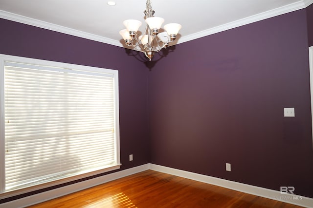 spare room with baseboards, wood finished floors, a notable chandelier, and ornamental molding