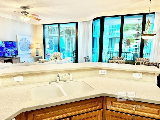 kitchen with brown cabinets, open floor plan, decorative light fixtures, light countertops, and a sink