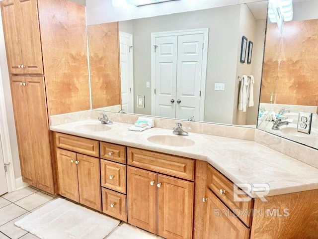 bathroom featuring tile patterned flooring, a closet, a sink, and double vanity