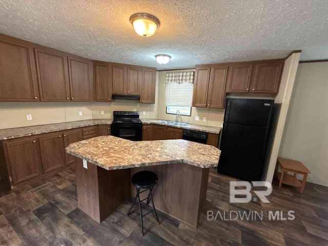 kitchen with sink, dark hardwood / wood-style floors, black appliances, light stone countertops, and a kitchen island