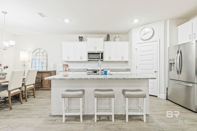 kitchen featuring light hardwood / wood-style floors, stainless steel appliances, and an island with sink