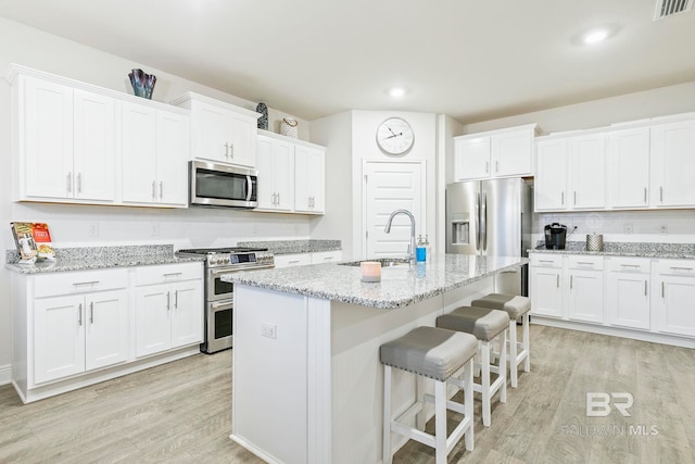 kitchen featuring white cabinets, appliances with stainless steel finishes, light hardwood / wood-style flooring, and sink