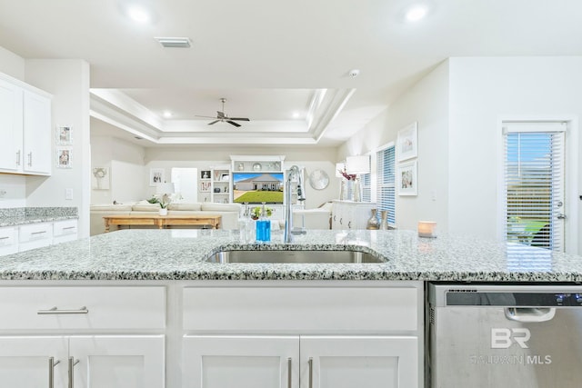 kitchen with light stone countertops, sink, a raised ceiling, stainless steel dishwasher, and white cabinets