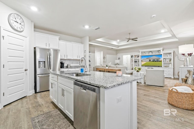 kitchen featuring white cabinets, a kitchen island with sink, sink, and appliances with stainless steel finishes