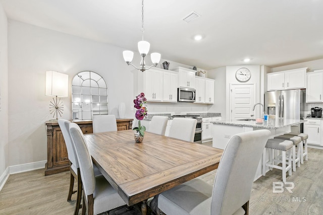 dining room with light wood-type flooring, sink, and a chandelier