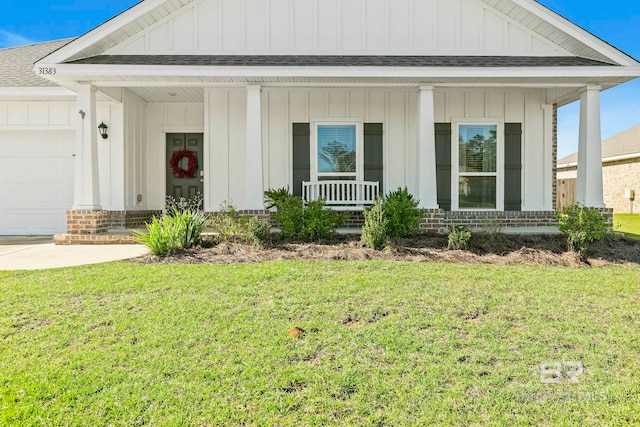 view of front facade featuring covered porch, a front yard, and a garage