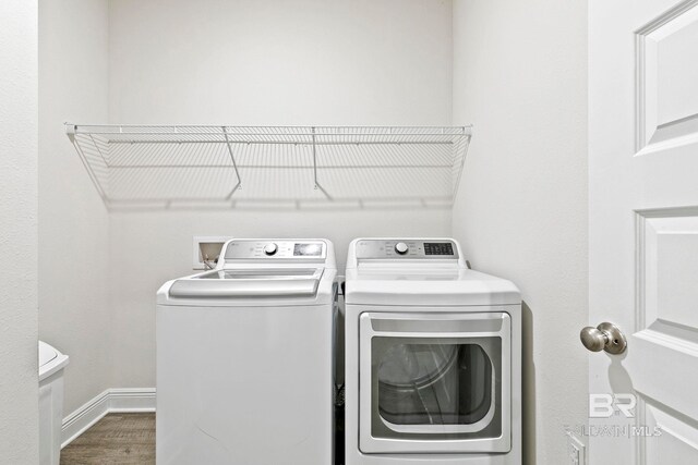 clothes washing area featuring washing machine and clothes dryer and dark hardwood / wood-style floors