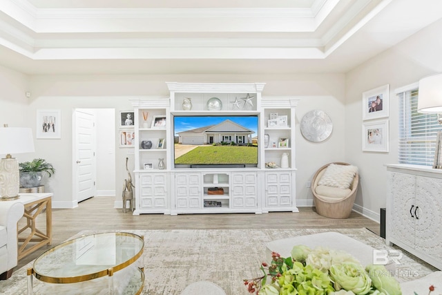 living room with light wood-type flooring, a tray ceiling, and crown molding