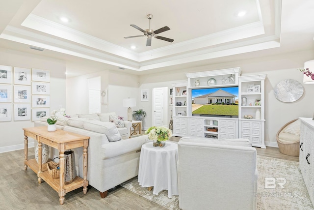 living room featuring light hardwood / wood-style flooring, a raised ceiling, and ceiling fan