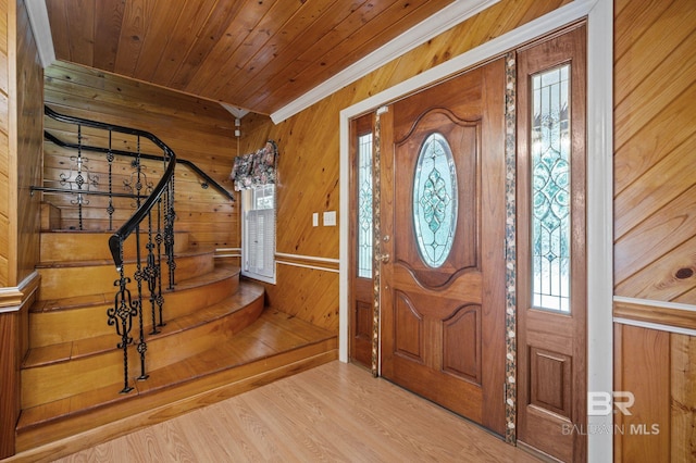 entrance foyer featuring a healthy amount of sunlight, crown molding, wood walls, wooden ceiling, and hardwood / wood-style flooring