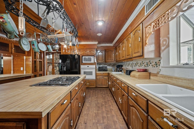 kitchen featuring hardwood / wood-style flooring, decorative backsplash, crown molding, white appliances, and butcher block countertops