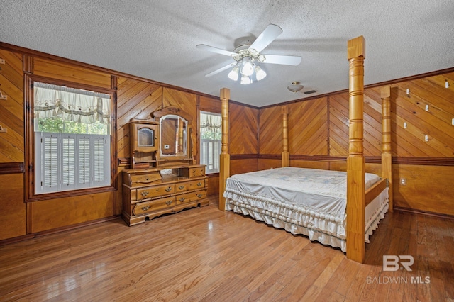 bedroom featuring wood walls, multiple windows, and hardwood / wood-style floors