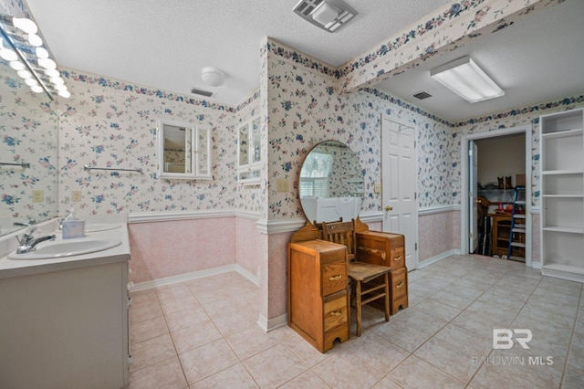 bathroom with tile patterned flooring, vanity, and a textured ceiling