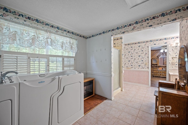 laundry area featuring light hardwood / wood-style floors, washer / clothes dryer, a textured ceiling, and ceiling fan