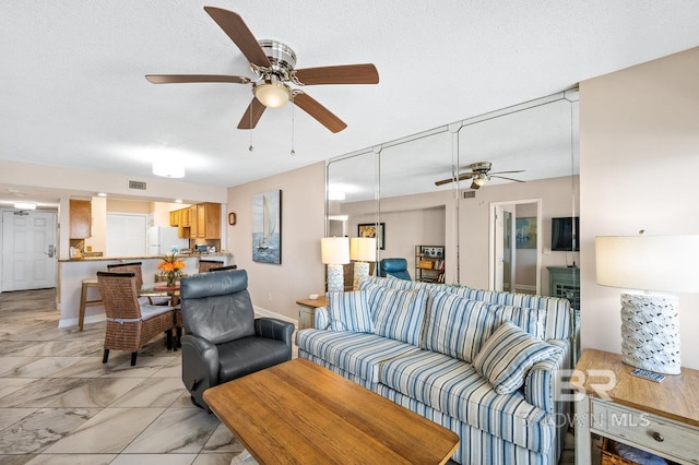 living room with a textured ceiling and ceiling fan