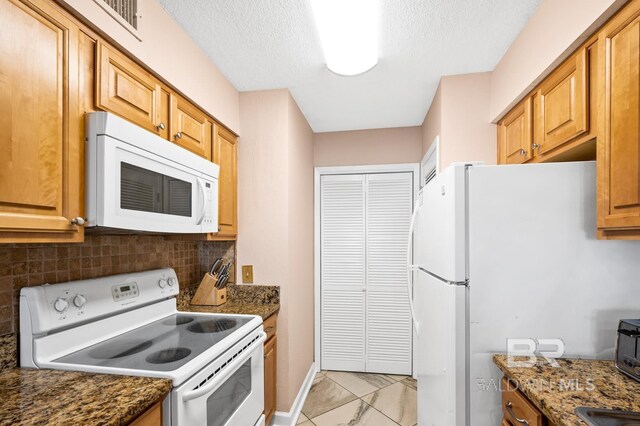 kitchen featuring white appliances, a textured ceiling, backsplash, and dark stone counters