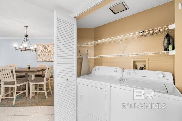 clothes washing area with washer and dryer, a notable chandelier, light tile flooring, hookup for a washing machine, and crown molding