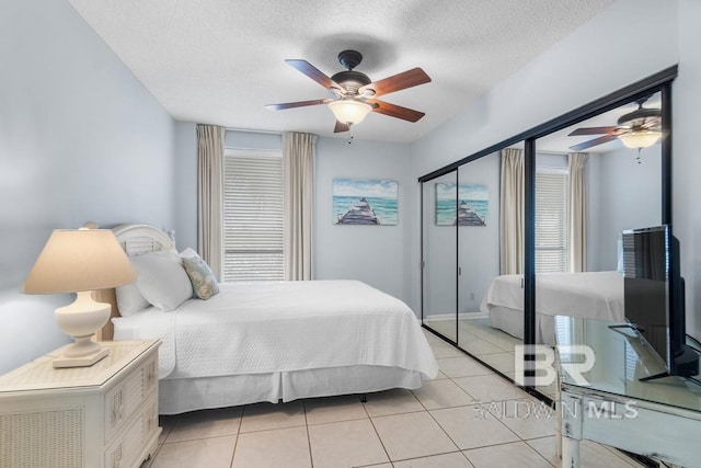 tiled bedroom with ceiling fan and a textured ceiling