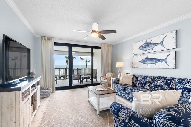 living room featuring ceiling fan, light tile floors, a textured ceiling, expansive windows, and crown molding