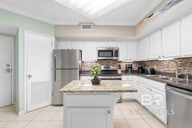 kitchen featuring appliances with stainless steel finishes, a kitchen island, sink, backsplash, and light tile flooring