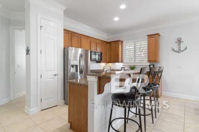 200 Peninsula Blvd Unit E101, Gulf Shores, AL 36542 - kitchen featuring a breakfast bar, black microwave, brown cabinets, light tile patterned floors, and crown molding