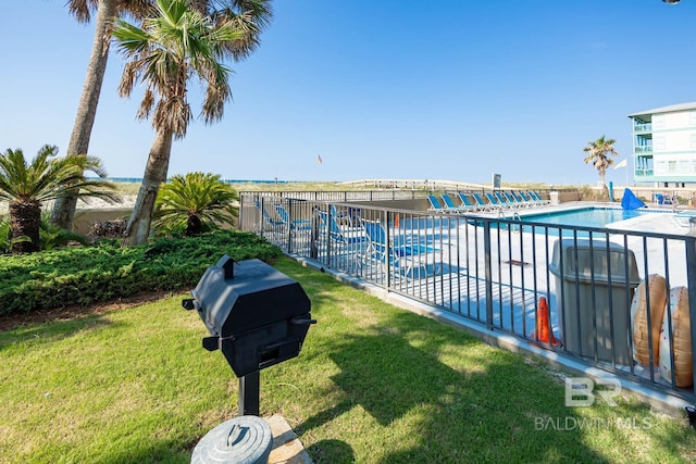 view of pool featuring a grill and a yard