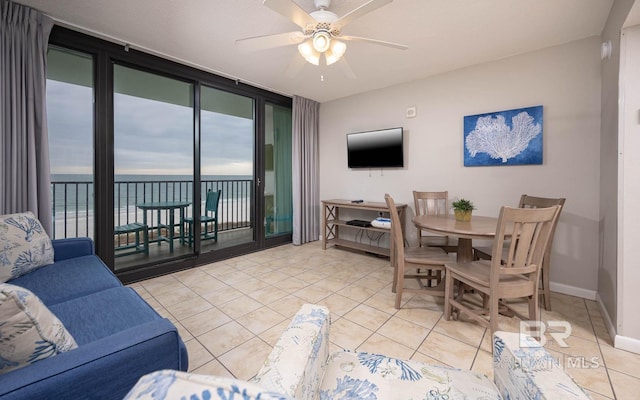 living room featuring a water view, ceiling fan, light tile patterned flooring, and a wall of windows