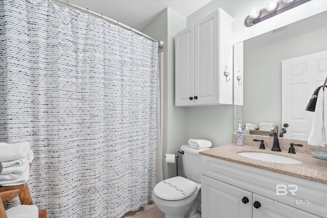 bathroom with tile patterned flooring, vanity, toilet, and walk in shower
