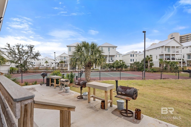 view of property's community with a yard and tennis court