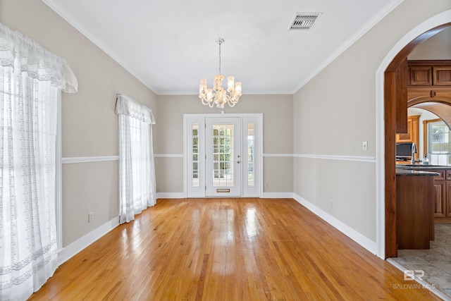 unfurnished dining area with light hardwood / wood-style floors, plenty of natural light, a notable chandelier, and ornamental molding