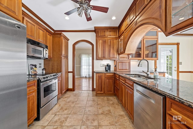 kitchen featuring crown molding, dark stone counters, appliances with stainless steel finishes, sink, and ceiling fan