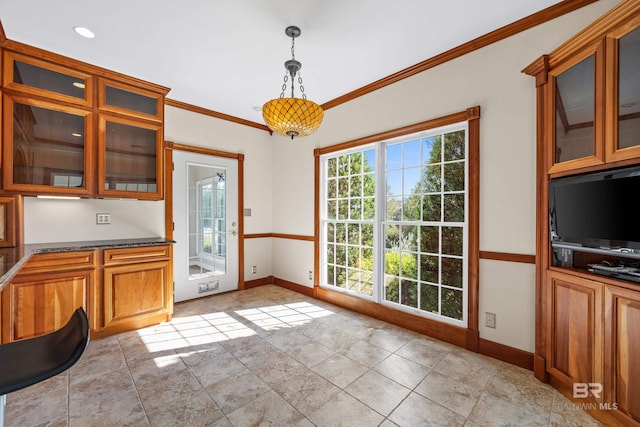 kitchen featuring dark stone countertops, pendant lighting, and ornamental molding