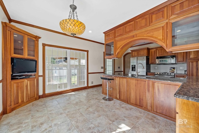 kitchen with kitchen peninsula, hanging light fixtures, ornamental molding, appliances with stainless steel finishes, and dark stone countertops